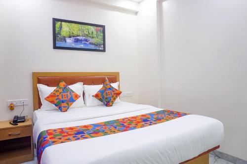 a bedroom with a large white bed with colorful pillows at FabHotel Falcon Executive - Pan card club road in Pune