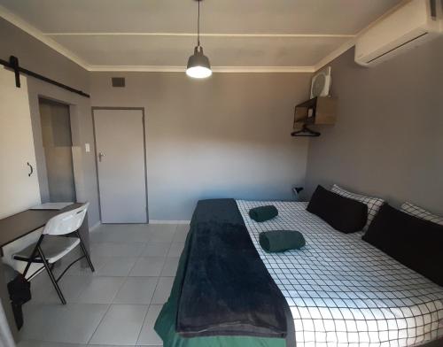 a small bedroom with a bed and a desk at Honeysuckle Manor in Richards Bay