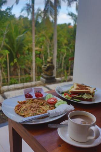 a table with two plates of food and a cup of coffee at Kelingking Beach Villas in Nusa Penida