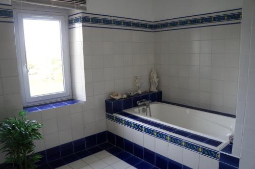 - une salle de bains bleue et blanche avec baignoire et fenêtre dans l'établissement cottage blanchou, à Galapian