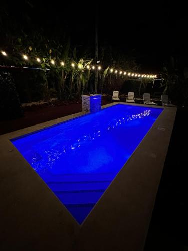 a blue swimming pool at night with lights at ApartHotel Villa Pacande & Rooms in Alajuela City