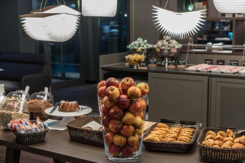 a table with a vase of apples and pastries at Motel One Dresden - Palaisplatz in Dresden