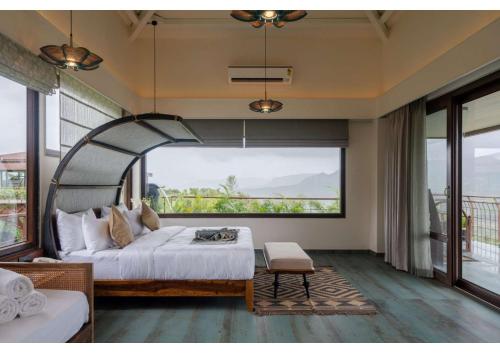 a bedroom with a bed and a large window at Malhar Machi Mountain Resorts in Mulshi