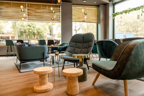 a waiting room with chairs and tables and windows at Motel One Wiesbaden in Wiesbaden