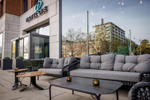 a patio with couches and tables in front of a building at Motel One Wiesbaden in Wiesbaden