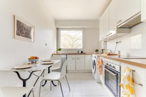 une cuisine avec des armoires blanches et une table et des chaises dans l'établissement Bel Espace, Paris-saclay, Visite Famille Business, à Gif-sur-Yvette