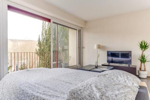 une chambre avec un grand lit et une grande fenêtre dans l'établissement Bel Espace, Paris-saclay, Visite Famille Business, à Gif-sur-Yvette
