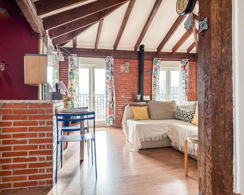 a living room with a couch and a brick wall at Acogedor loft con vistas a la ciudad in Santander