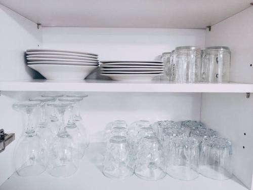 a white shelf filled with lots of glass jars and plates at Magnifique Appartement T3 50 m2 in Obernai