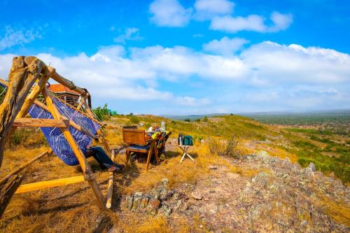a group of people sitting at a table on a hill at Kigarama Wilderness Lodge Mburo in Bakijurura