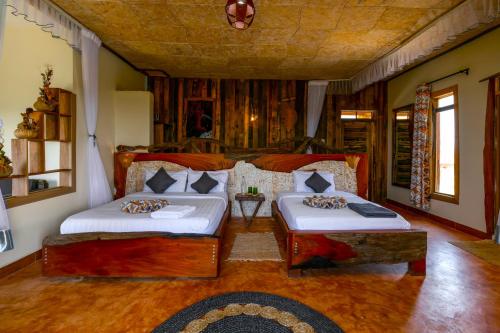 a bedroom with two beds and a couch at Kigarama Wilderness Lodge Mburo in Bakijurura
