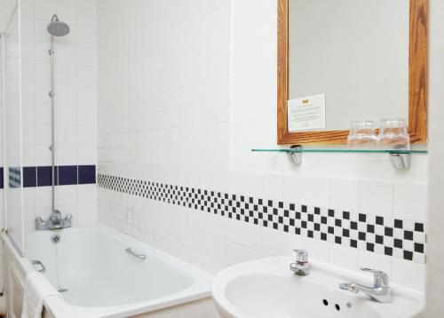 a bathroom with two sinks and a tub and a mirror at Sun Hotel by Greene King Inns in Hitchin