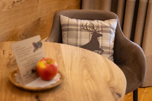 an apple on a plate on a table next to a pillow at Hotel Relais Des Glaciers - Adults Only in Champoluc