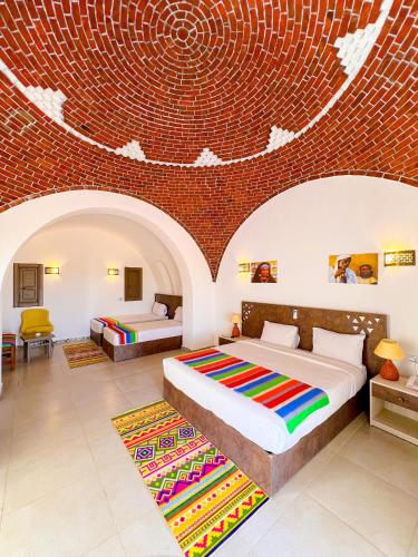 a bedroom with two beds and a brick wall at Beach safari nubian resort in Marsa Alam City