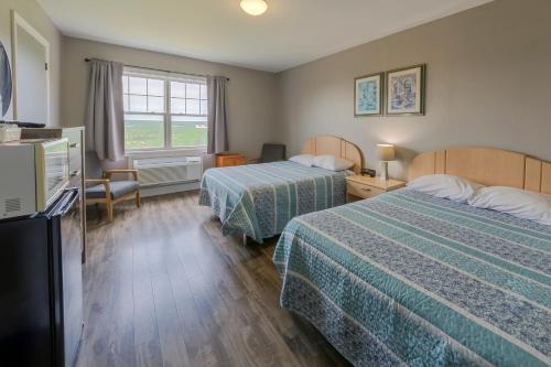a hotel room with two beds and a television at Auberge Doucet Inn in Chéticamp