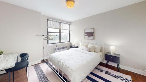 a white bedroom with a bed and a desk and a window at Avenue A810 Epic 2br, Pool, Gym, Parking in Philadelphia
