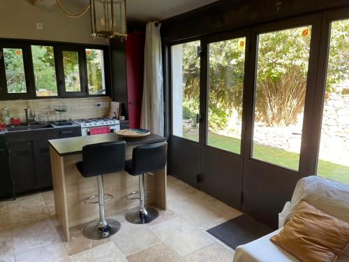 une cuisine avec une table et deux tabourets de bar dans l'établissement Charmante Maison au cœur du village, à Rustrel