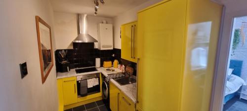 a yellow kitchen with a sink and a stove at The Hideaway Cottage Feel Patio Central Parking in Southport