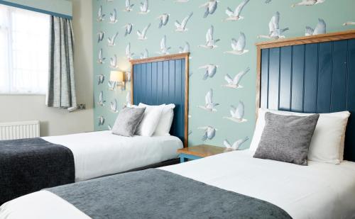 two beds in a room with birds on the wall at Sun Hotel by Greene King Inns in Hitchin