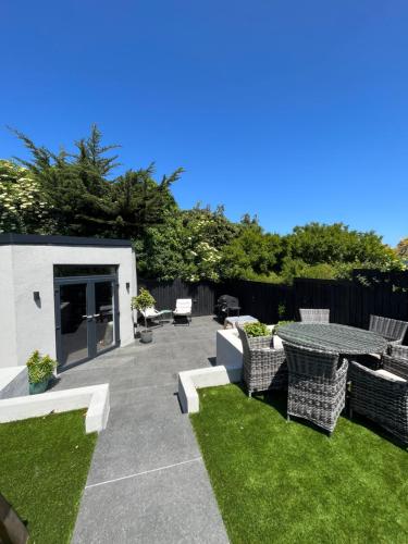 a patio with a table and chairs and grass at Modern 4 bedroom house south Dublin in Blackrock