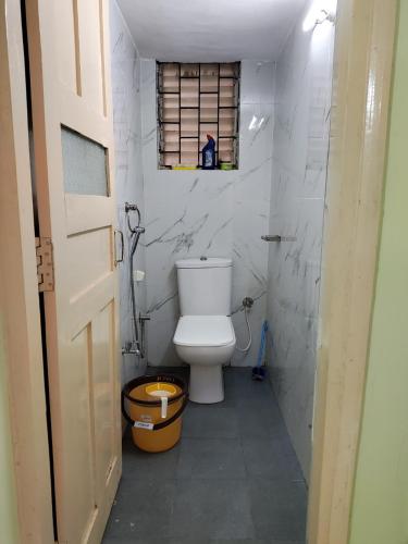 a bathroom with a white toilet and a window at Serene Homestay in Panaji