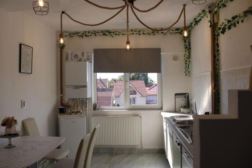 Una cocina con una mesa, una ventana y un fregadero. en The One Apartments, en Tăşnad