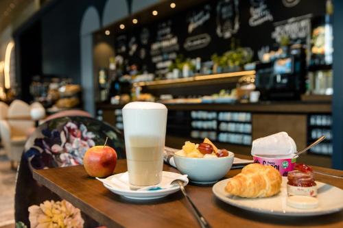 a table with two plates of food and a drink at Motel One Dresden am Zwinger in Dresden