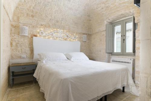 a bedroom with a white bed and a window at Casetta Wilma by Wonderful Italy in Cisternino