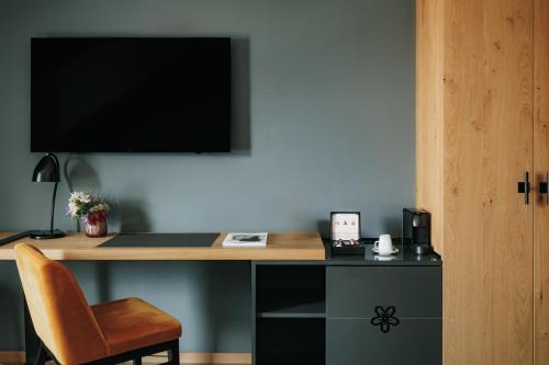 a desk with a monitor and a chair in a room at AMERON Neuschwanstein Alpsee Resort & Spa in Schwangau