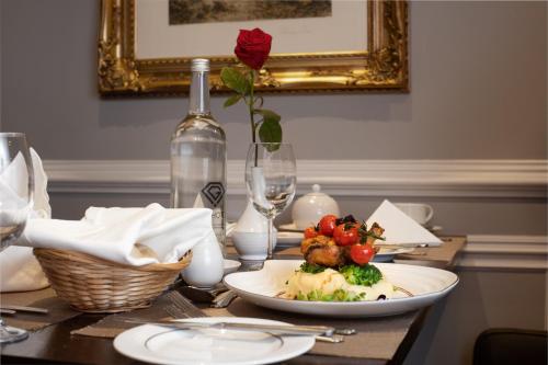 a table with a plate of food and a red rose at Gem Fitzrovia Hotel in London