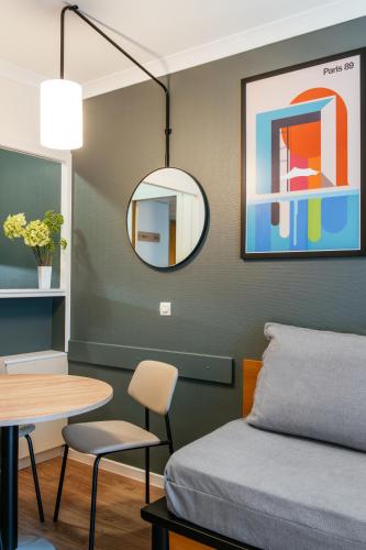 a room with a bed and a table and a mirror at Aparthotel Adagio La Défense Le Parc in Courbevoie