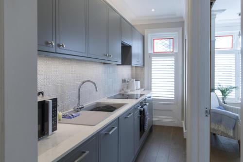 a kitchen with white cabinets and a sink at Grove Apartment with Free on street Parking in Worthing