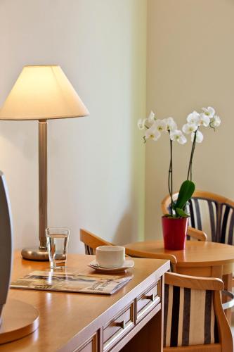 a table with a lamp and a vase with white flowers at Civitel Attik Rooms & Suites in Athens