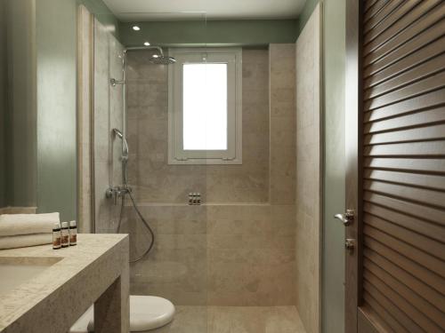 a bathroom with a shower and a toilet and a sink at Civitel Attik Rooms & Suites in Athens