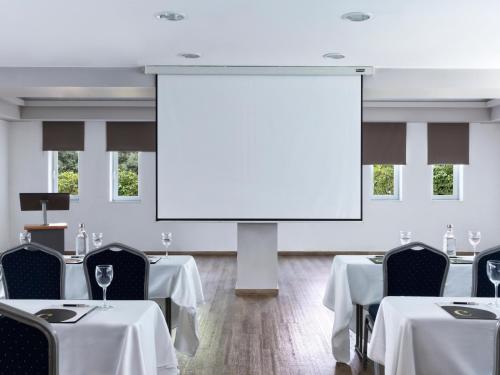 a conference room with tables and a large screen at Civitel Attik Rooms & Suites in Athens