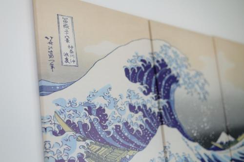 a blue and white painting of a wave on a wall at Rana片瀬江ノ島 in Fujisawa