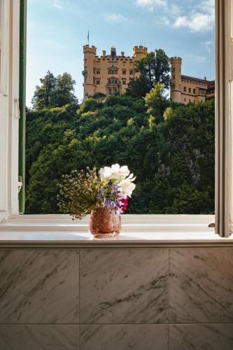 a vase of flowers sitting on a window sill at AMERON Neuschwanstein Alpsee Resort & Spa in Schwangau