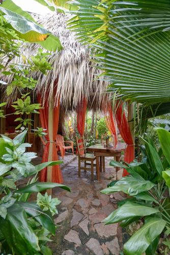 a patio with a table and chairs and a palm tree at CHALET TROPICAL Hotel & Restaurant-Pizzeria in Las Galeras