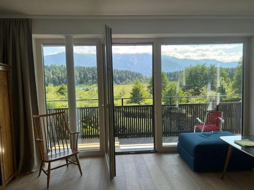 a room with a view of a balcony with a chair at Seehaus Herzog in Drobollach am Faakersee