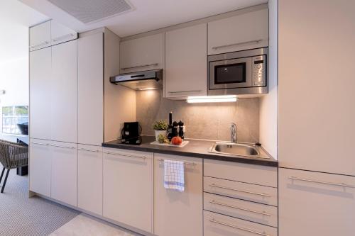 a kitchen with white cabinets and a sink at SlowDown Bottsand Hotel und Spa in Wendtorf