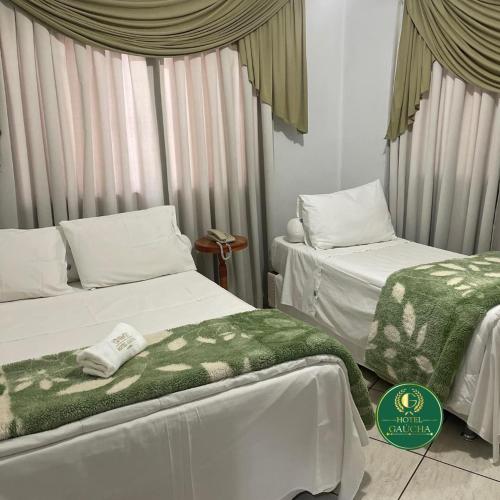 a bedroom with two beds with green and white sheets at Hotel Gaucha in Guaíra