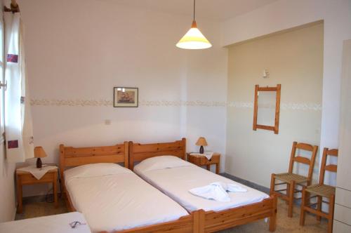 a bedroom with two beds and two chairs at Pyrgis Studios in Glifades