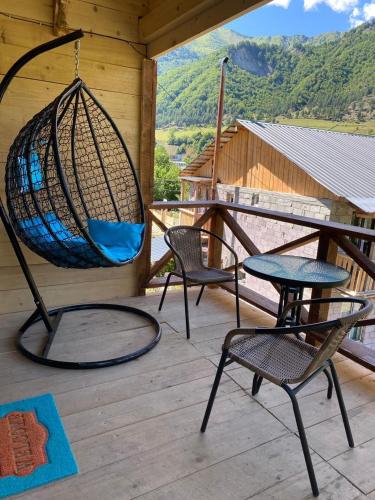 a porch with two chairs and a swing at COTTAGE cozy side in Mestia