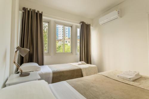 a white bedroom with two beds and a window at Apartamento Charmoso no Centro da Cidade P957 in Florianópolis