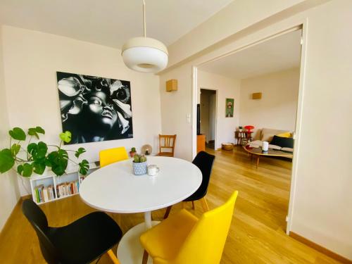 un salon avec une table blanche et des chaises jaunes dans l'établissement Appartement rosaluz, à Montpellier