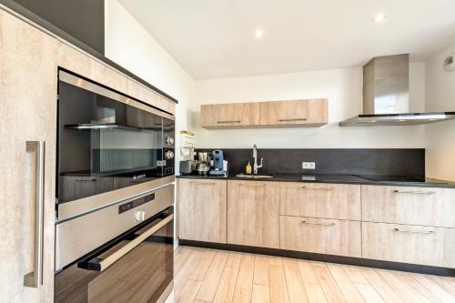 a kitchen with wooden cabinets and stainless steel appliances at Maison récente à 300 m de la mer in Carantec
