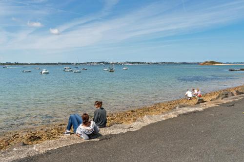 a group of people sitting on the shore of a body of water at Maison récente à 300 m de la mer in Carantec