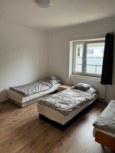 three beds in a room with a window at Széchenyi vendégház in Sajószöged
