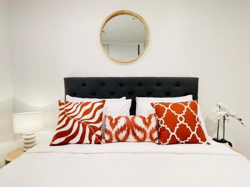 1 cama con almohadas de color naranja y blanco y espejo en CBD High-rise beautiful View apartment, en Auckland