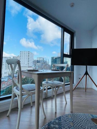Una mesa y sillas en una habitación con una ventana grande. en CBD High-rise beautiful View apartment, en Auckland